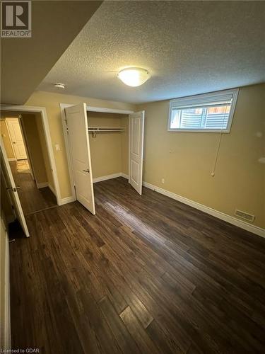 Unfurnished bedroom featuring a textured ceiling, dark hardwood / wood-style floors, and a closet - 111 Dallan Drive, Guelph, ON - Indoor Photo Showing Other Room