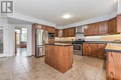 Kitchen featuring stainless steel appliances, wall chimney exhaust hood, and a kitchen island - 