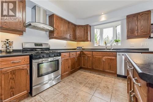 Kitchen featuring wall chimney range hood, sink, light tile patterned floors, and stainless steel appliances - 43 Marr Drive, Elora, ON - Indoor Photo Showing Kitchen