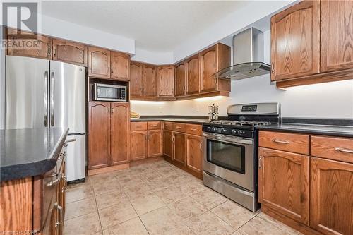 Kitchen featuring wall chimney exhaust hood, light tile patterned floors, and stainless steel appliances - 43 Marr Drive, Elora, ON - Indoor Photo Showing Kitchen