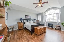 Bedroom featuring a wood stove, ceiling fan, vaulted ceiling with beams, and dark hardwood / wood-style flooring - 