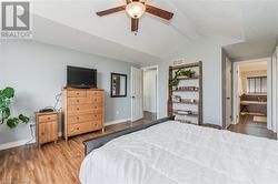 Bedroom with ensuite bath, a textured ceiling, hardwood / wood-style flooring, ceiling fan, and lofted ceiling with beams - 