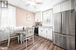 Kitchen featuring wood-type flooring, stainless steel appliances, white cabinetry, a paneled ceiling, and ceiling fan - 