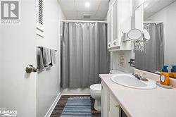 Full bathroom featuring a drop ceiling, shower / bath combo, wood-type flooring, toilet, and vanity - 