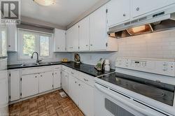 Kitchen featuring white cabinetry, sink, light parquet flooring, white range with electric cooktop, and decorative backsplash - 