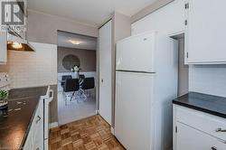 Kitchen with white cabinets, white appliances, backsplash, and light parquet flooring - 