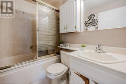 Full bathroom featuring toilet, vanity, and bath / shower combo with glass door - 