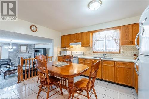 Kitchen with sink, tasteful backsplash, light tile patterned floors, an inviting chandelier, and white appliances - 46 Mark Place, Hamilton, ON 