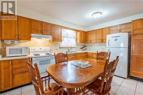 Kitchen with backsplash, white appliances, sink, and light tile patterned flooring - 46 Mark Place, Hamilton, ON 