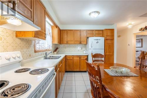 Kitchen with sink, white appliances, backsplash, and light tile patterned floors - 46 Mark Place, Hamilton, ON 