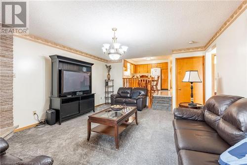 Carpeted living room with an inviting chandelier, a textured ceiling, and crown molding - 46 Mark Place, Hamilton, ON 