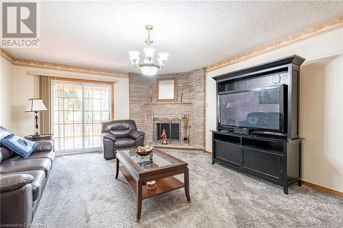 Living room with a fireplace, a chandelier, a textured ceiling, and carpet floors - 46 Mark Place, Hamilton, ON 