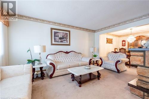 Living room featuring carpet floors, a textured ceiling, crown molding, and an inviting chandelier - 46 Mark Place, Hamilton, ON 