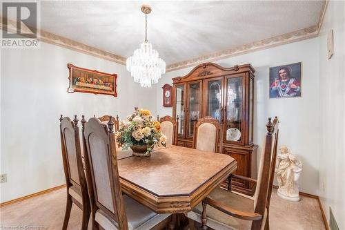 Dining room with light colored carpet, a textured ceiling, and a notable chandelier - 46 Mark Place, Hamilton, ON 