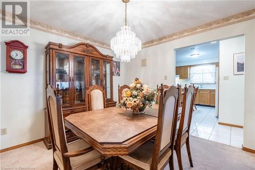 Dining room featuring light colored carpet, a textured ceiling, and a notable chandelier - 46 Mark Place, Hamilton, ON 