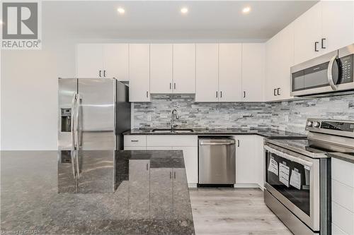 Kitchen with stainless steel appliances, white cabinets, sink, light hardwood / wood-style flooring, and dark stone countertops - 1023 Devonshire Avenue Unit# 3, Woodstock, ON - Indoor Photo Showing Kitchen With Upgraded Kitchen