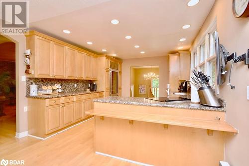 Kitchen featuring a kitchen bar, light hardwood / wood-style floors, kitchen peninsula, backsplash, and light brown cabinetry - 264 Salem Road, Barrie, ON 