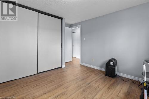 Unfurnished bedroom with light hardwood / wood-style floors, a textured ceiling, and a closet - 253 Auden Road, Guelph, ON - Indoor Photo Showing Other Room