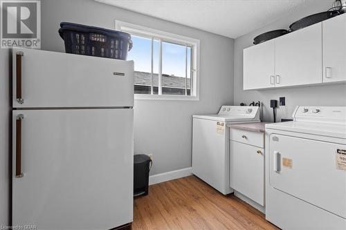 Laundry room with cabinets, separate washer and dryer, a textured ceiling, and light wood-type flooring - 253 Auden Road, Guelph, ON - Indoor Photo Showing Laundry Room