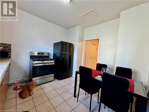 Kitchen with light tile patterned flooring, stainless steel range with gas stovetop, and black fridge - 21 Minto Avenue, Hamilton, ON 