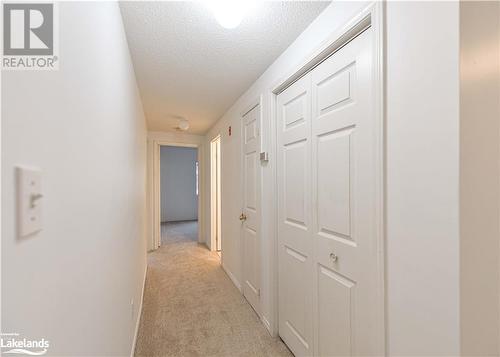 Hallway featuring a textured ceiling and light carpet - 107 Bond Street Unit# 201, Orillia, ON - Indoor Photo Showing Other Room