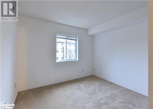 Empty room with a textured ceiling and light colored carpet - 107 Bond Street Unit# 201, Orillia, ON - Indoor Photo Showing Other Room