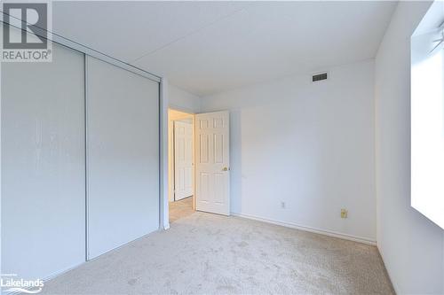 Unfurnished bedroom featuring light carpet and a closet - 107 Bond Street Unit# 201, Orillia, ON - Indoor Photo Showing Other Room