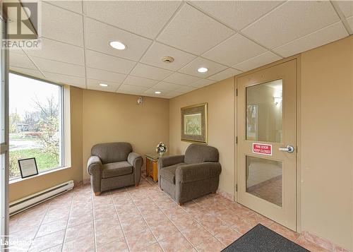 Sitting room featuring a paneled ceiling, light tile patterned floors, and a baseboard heating unit - 107 Bond Street Unit# 201, Orillia, ON - Indoor