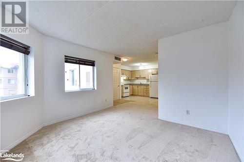 Unfurnished living room with a textured ceiling and light carpet - 107 Bond Street Unit# 201, Orillia, ON - Indoor Photo Showing Other Room