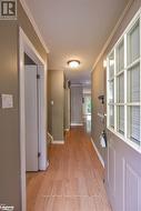 Hallway with a textured ceiling, light hardwood / wood-style flooring, and crown molding - 