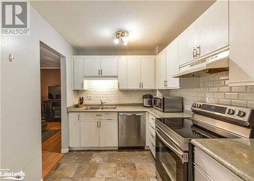 Kitchen with decorative backsplash, sink, white cabinetry, and appliances with stainless steel finishes - 441 Barrie Road Unit# 34, Orillia, ON - Indoor Photo Showing Kitchen With Double Sink