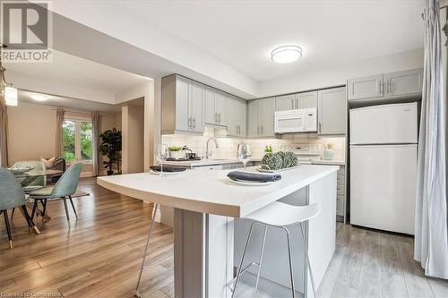 Kitchen with white appliances, a kitchen bar, light wood-type flooring, and tasteful backsplash - 130 Livingston Avenue Unit# 21, Grimsby, ON - Indoor Photo Showing Kitchen