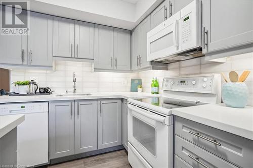 Kitchen with sink, white appliances, dark wood-type flooring, gray cabinetry, and decorative backsplash - 130 Livingston Avenue Unit# 21, Grimsby, ON - Indoor Photo Showing Kitchen