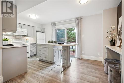 Kitchen featuring gray cabinetry, white appliances, light hardwood / wood-style floors, and a breakfast bar area - 130 Livingston Avenue Unit# 21, Grimsby, ON - Indoor Photo Showing Kitchen