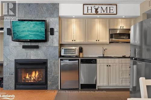 52-107 - 1235 Deerhurst Drive, Huntsville (Chaffey), ON - Indoor Photo Showing Kitchen With Fireplace