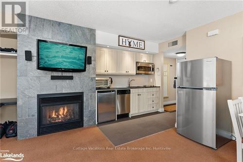 52-107 - 1235 Deerhurst Drive, Huntsville (Chaffey), ON - Indoor Photo Showing Kitchen With Fireplace