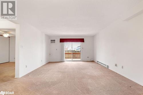 Carpeted empty room featuring ceiling fan, a wall mounted AC, and a baseboard radiator - 73 Lywood Street Unit# 2, Belleville, ON - Indoor Photo Showing Other Room