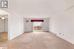 Carpeted empty room featuring ceiling fan, a wall mounted AC, and a baseboard radiator - 