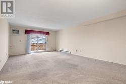 Spare room with light colored carpet, a wall mounted air conditioner, and a baseboard heating unit - 