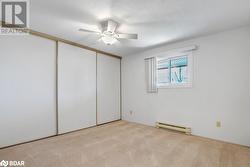 Unfurnished bedroom with a closet, a textured ceiling, light carpet, baseboard heating, and ceiling fan - 