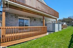 Back of house with a storage shed, a wooden deck, and a lawn - 