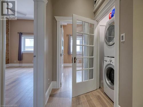 Laundry area with stacked washing maching and dryer, french doors, and light wood-type flooring - 151 Thames Street S, Ingersoll, ON 