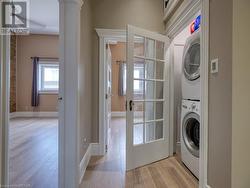 Laundry area with stacked washing maching and dryer, french doors, and light wood-type flooring - 