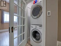 Laundry room featuring light hardwood / wood-style floors and stacked washer / drying machine - 