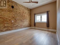 Spare room with light wood-type flooring, brick wall, and ceiling fan - 