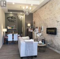 Living room with a large fireplace, a notable chandelier, dark hardwood / wood-style floors, and a raised ceiling - 