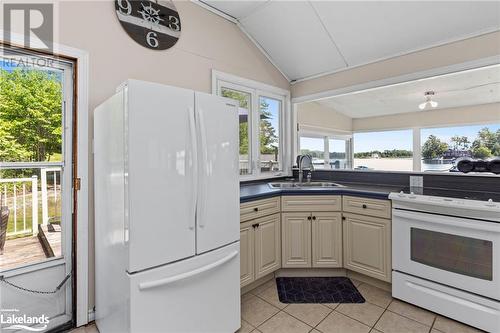 Kitchen with light tile patterned flooring, white appliances, sink, and lofted ceiling - 68 Wolverine Beach Rd, Port Severn, ON - Indoor Photo Showing Kitchen With Double Sink