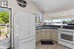 Kitchen with light tile patterned flooring, white appliances, sink, and lofted ceiling - 