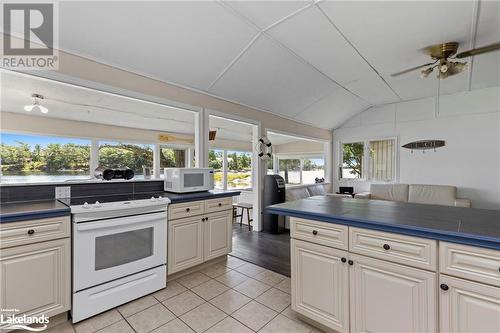 Kitchen featuring white appliances, ceiling fan, vaulted ceiling, and light tile patterned flooring - 68 Wolverine Beach Rd, Port Severn, ON - Indoor Photo Showing Kitchen