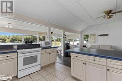 Kitchen featuring white appliances, ceiling fan, vaulted ceiling, and light tile patterned flooring - 